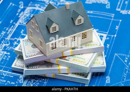 House on Top of a Stack of Cash and Blueprints. Stock Photo