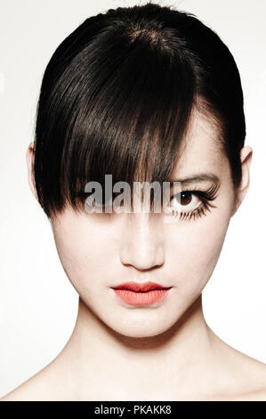 A beautiful woman with dark hair and a fringe looking at camera in make-up reminiscent of Clockwork Orange. Stock Photo