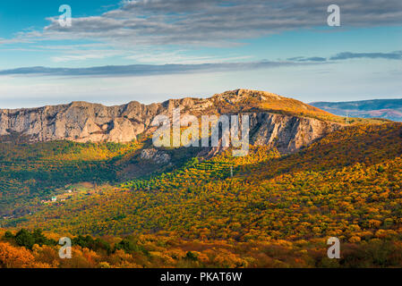 Beautiful autumn scenic landscape - orange forest and rocky mountains in the sun Stock Photo