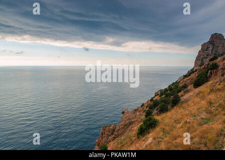 Dramatic sky, rocky coast and calm sea before the storm Stock Photo