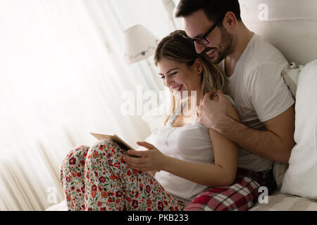 Young attractive couple using tablet in bedroom Stock Photo