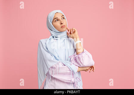 The arab woman in hijab. Portrait of serious girl, posing at pink studio background. Young emotional woman. The human emotions, facial expression concept. Front view. Stock Photo