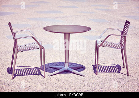 Two chairs by an empty table, color toned picture. Stock Photo