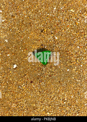 Green triangle glass on the yellow sand, summer, morning Stock Photo