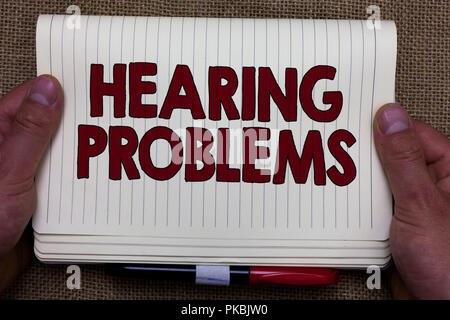 Handwriting text writing Hearing Problems. Concept meaning is partial or total inability to listen to sounds normally Man hands holding notebook open  Stock Photo