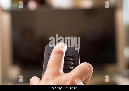 Yong man hand with remote changes channels Stock Photo