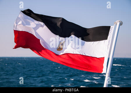 Egyptian Flag Floating in the Sun with Red Sea in the Background Stock Photo