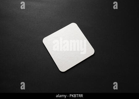 Blank square beer coaster mockup on black background. Stock Photo