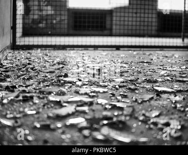 Shattered glass on the floor. With fence behind in background. Stock Photo