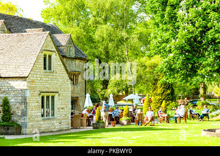 A country pub with outdoor seating and people and trees in The Cotswolds, England, UK Stock Photo