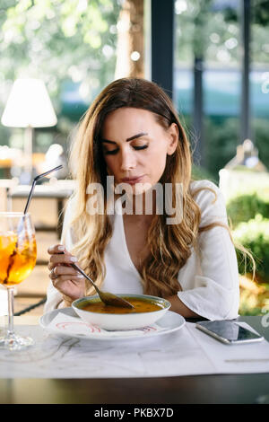 Young  attractive woman eating soup in restaurant