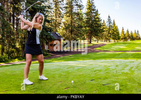 A female golfer at the top of her swing as she gets ready to hit the ball after setting up her shot; Edmonton, Alberta, Canada Stock Photo