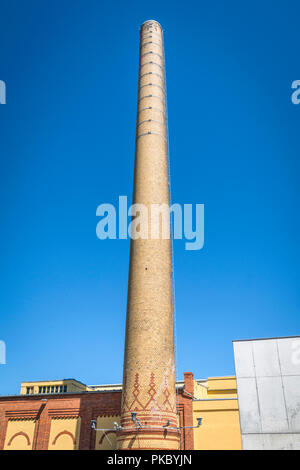 Tall chimney made of bricks on a factory under a blue sky Stock Photo