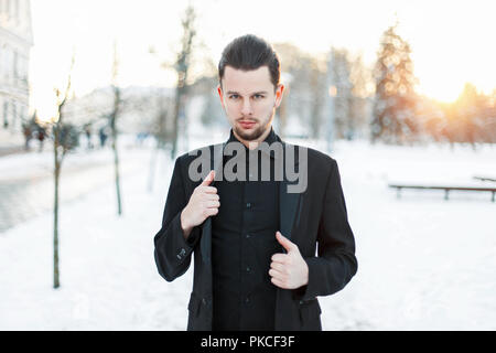 Handsome young man in a black suit at sunset Stock Photo