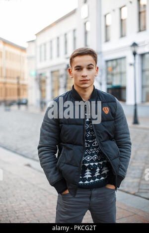 Young handsome man in winter clothes standing near the building, holding hands in pockets Stock Photo