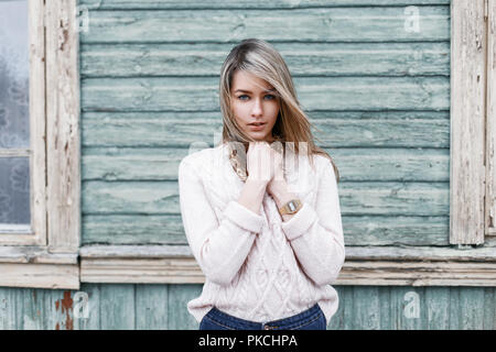 Modest young girl on the background of the old wooden wall with windows Stock Photo