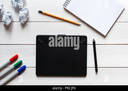Concept artist desktop. Graphics tablet, crumpled paper, notebook and markers on a white wooden table. View from above Stock Photo