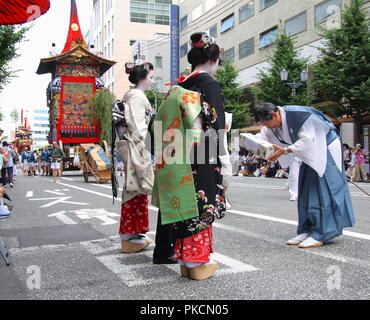 KYOTO - JULY 17, 2010: Two geishas receive a gift from a participant of the famous annual Gion Festival in Kyoto, Japan. Stock Photo