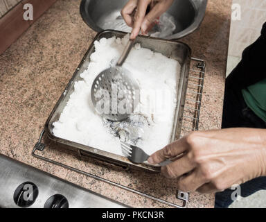 Removing salt from fish baked in coarse sea salt. Stock Photo