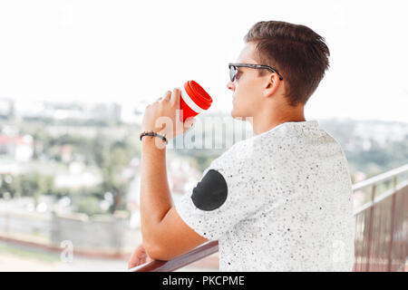 Handsome hipster man drinking coffee and looking at the city Stock Photo