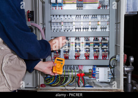 electrician at work with an electric panel Stock Photo