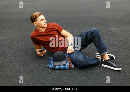 Handsome man with phone lying on the pavement and rests. Stock Photo