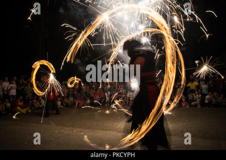 Djurdjevo, Serbia - September 07, 2018: Long exposure photo with dancing fire artists, entertaining crowd with fireworks an juggling torches. Stock Photo