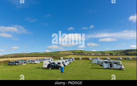Campervan on a green field with blue sky. Green camper beneath blue sky ...