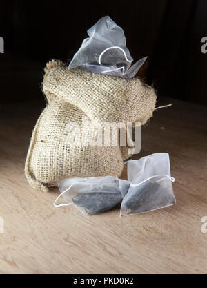 Bags of elite tea in silk fabric packing and tea mug on a wooden background Stock Photo