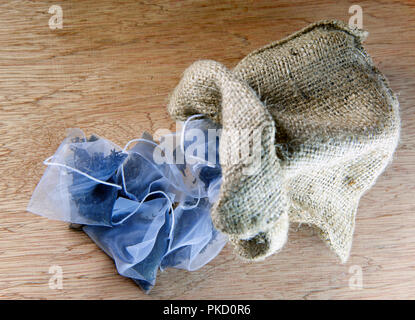 Bags of elite tea in silk fabric packing and tea mug on a wooden background Stock Photo