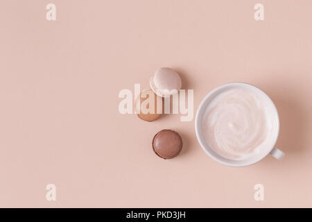 Cup of coffee with macaroons on pastel background, flat lay. Stock Photo