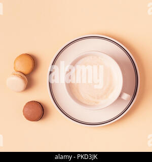 Cup of coffee with macaroons on pastel background, flat lay. Stock Photo