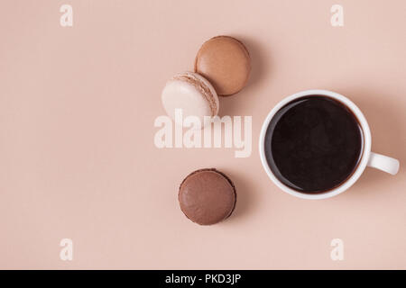 Cup of coffee with macaroons on pastel background, flat lay. Stock Photo