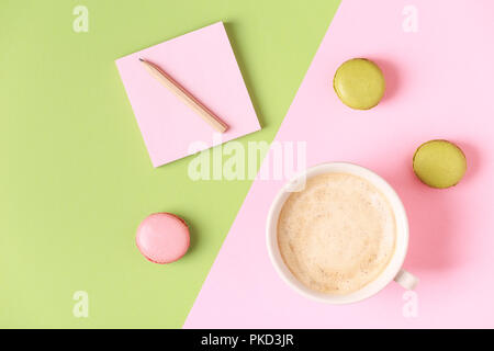 Cup of coffee with macaroons on pastel background, flat lay. Stock Photo