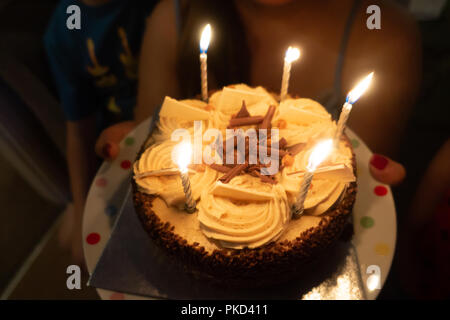A close up view of a chocolate birthday cake which has birthday candles burning on top. Stock Photo