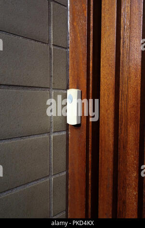 Plastic doorbell on strong wooden door Stock Photo