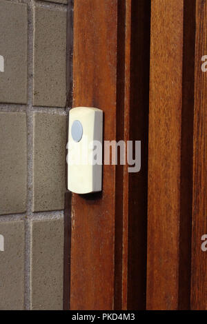 Plastic doorbell on strong wooden door Stock Photo