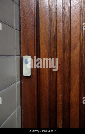 Plastic doorbell on strong wooden door Stock Photo