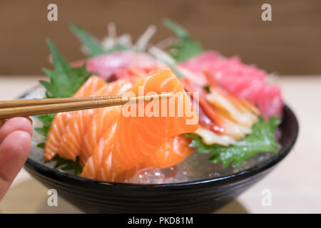 Mixed sliced fish sashimi on ice in black bowl. Sashimi Salmon Tuna Hamachi Prawn and Surf Calm set, raw fish, japanese food in Asian restaurant. Stock Photo