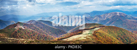 Panorama of colorful autumn forest in the mountain and heavy clouds in the sky. Stock Photo