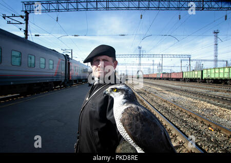 SIBERIA, RUSSIA - MARCH 20, 2018: The Russian man is doing a show at the train station with a hawk. Ulan Ude, Russia. Stock Photo