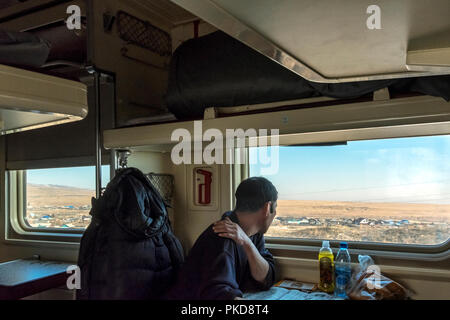 SIBERIA, RUSSIA - MARCH 20, 2018: The Russian passenger is watching outside from train. Khabarovsk, Russia.