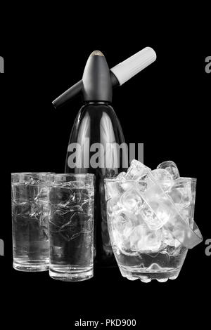 Black shiny metal table siphon for soda, next to a transparent bucket of ice and two glasses of mineral sparkling water, isolated black background, si Stock Photo