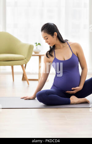 Cheerful pregnant woman practicing yoga at home Stock Photo
