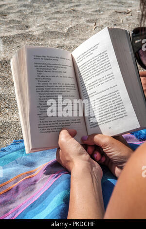 Reading a book on the beach-close-up Stock Photo