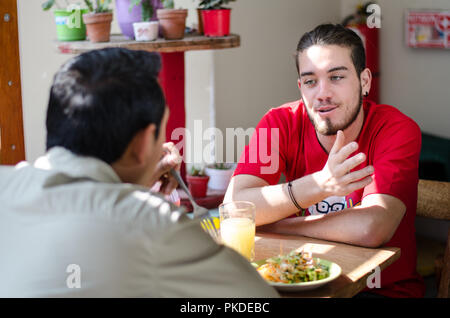 Good looking men having lunch in an outdoor restaurant, men chatting and smiling Stock Photo