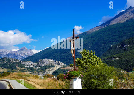 Crucifix by the road side and view towards Fort Victor-Emmanuel, Aussois, France Stock Photo