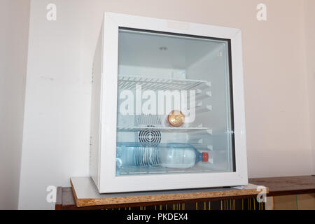 Soda can and water bottle in a mini-fridge with glass door in an hotel Stock Photo