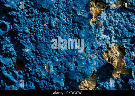 Yellow stone wall with dark blue plaster pealing off/grunge wall texture background Stock Photo