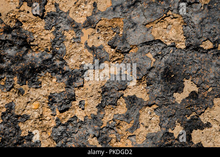 Yellow stone wall with dark paint pealing off/grunge wall texture background Stock Photo